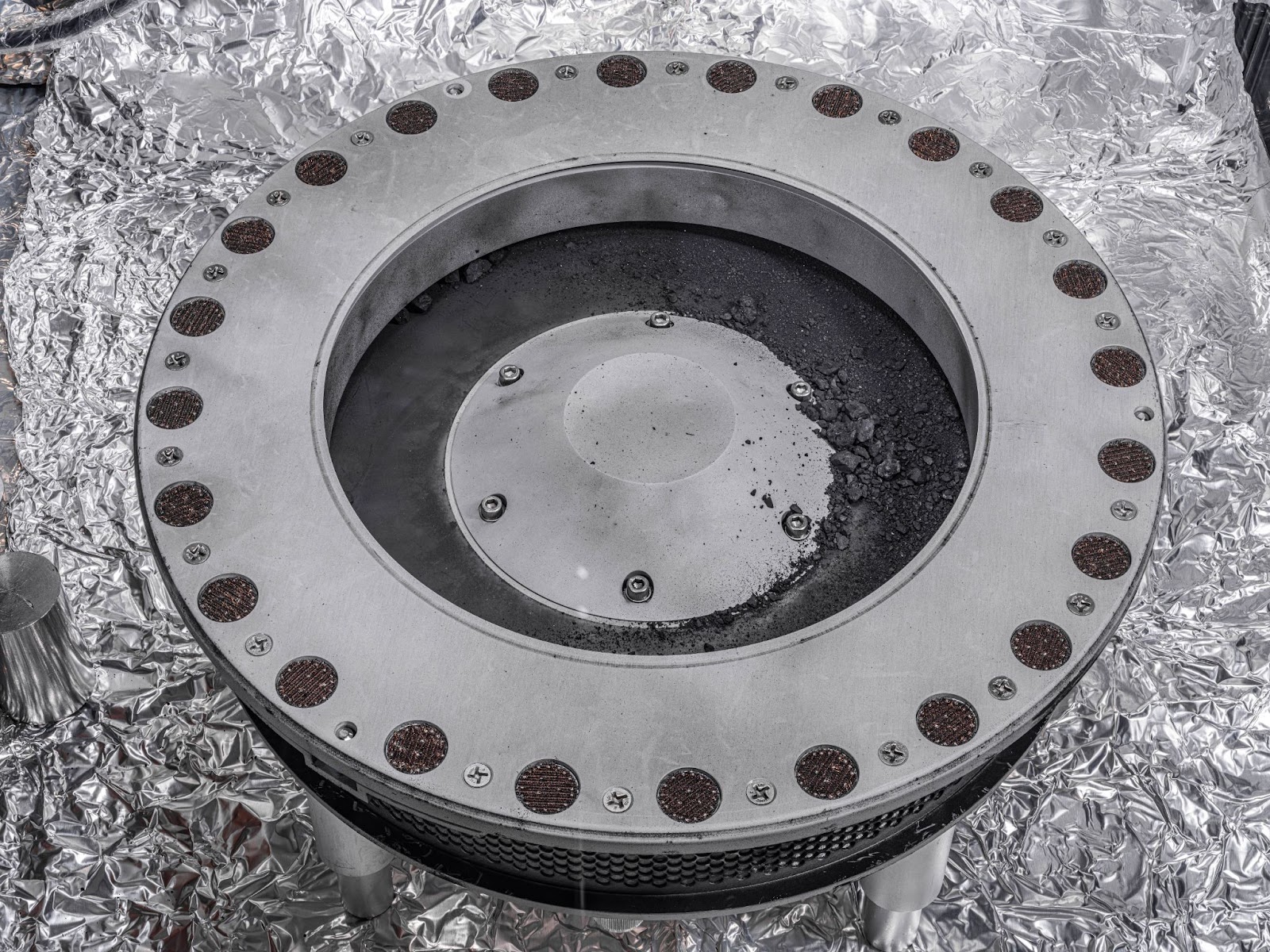 Un primer plano de un recipiente de metal que contiene piezas de la muestra del asteroide Bennu.