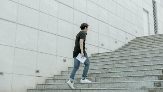 A man walking up the stairs with a notebook.