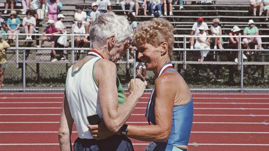Two older women standing next to each other on a track, questioning longevity.