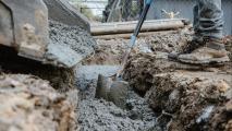 A man pouring concrete into a trench.