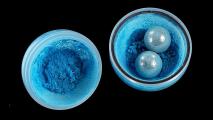 Two blue powders in a bowl on a black background undergoing mechanochemistry.