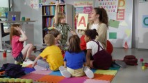 A group of children sitting on the floor in a classroom.