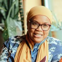 A woman wearing a hijab sitting on an orange couch.