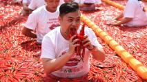 A man eating chili peppers in a red field.