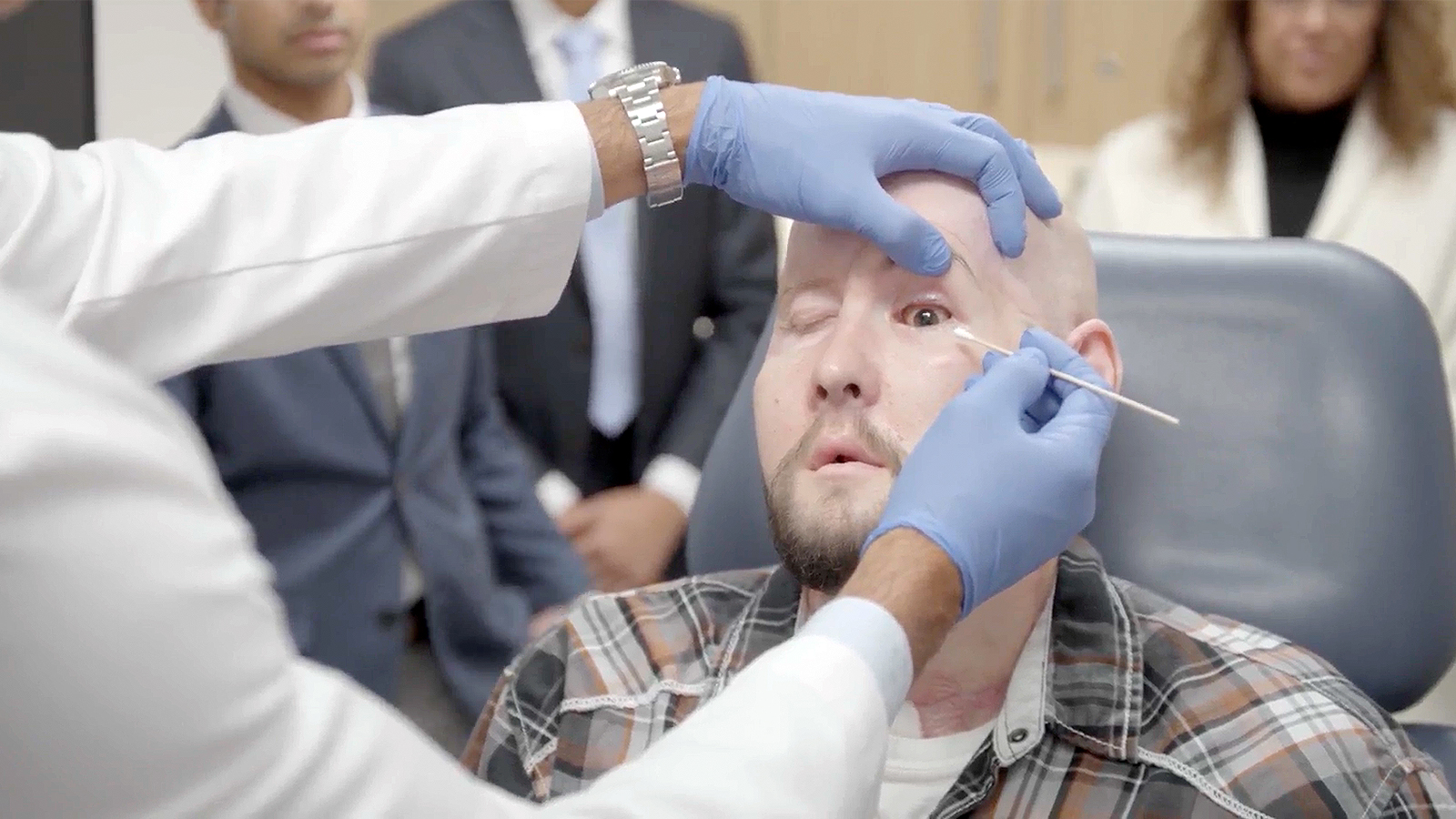 A bald man is having his eye examined by a doctor