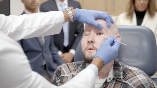 A bald man is having his eye examined by a doctor