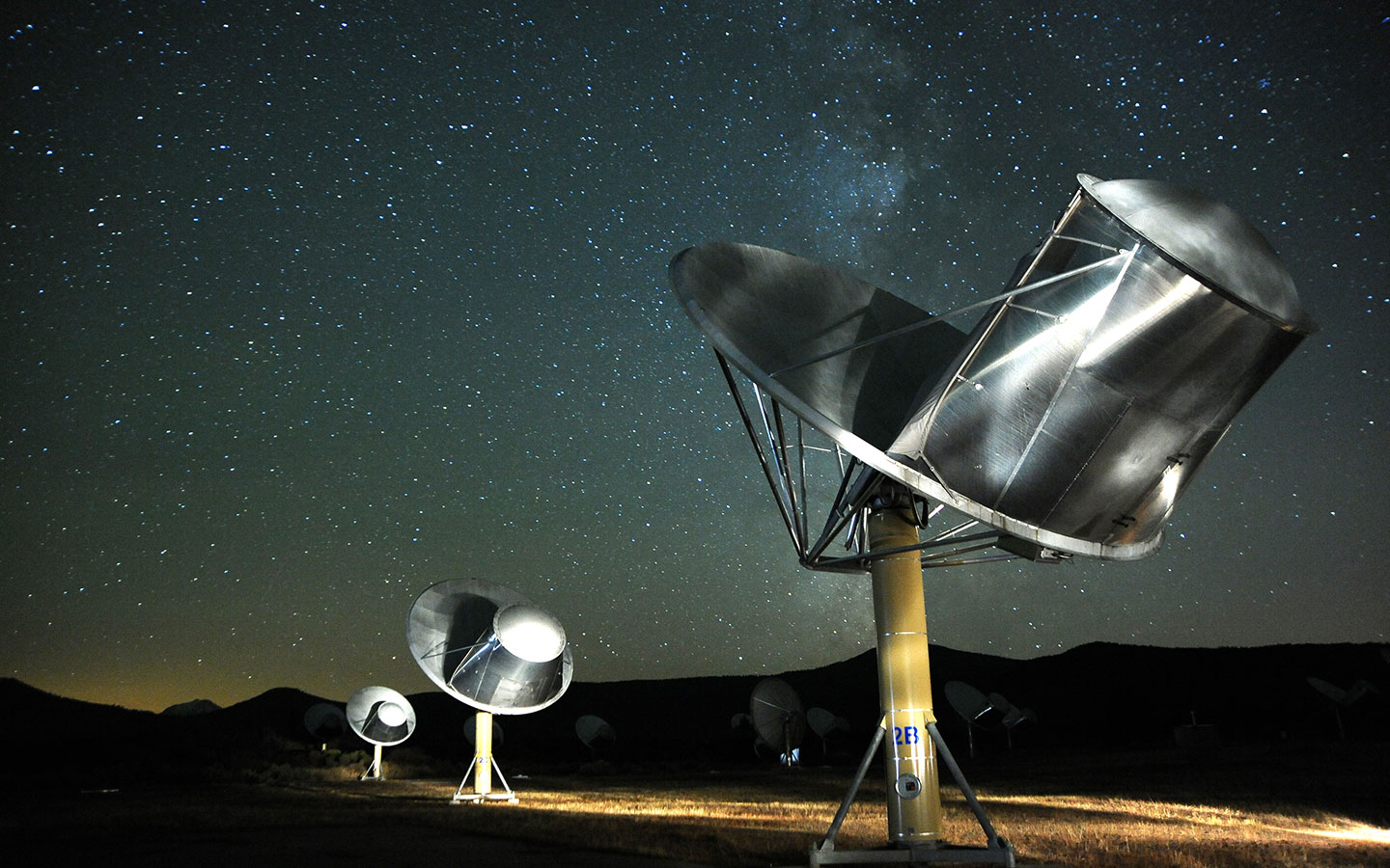 A group of satellite dishes under a starry sky.