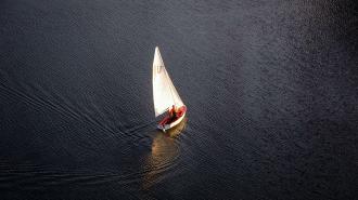 An aerial view of a sailboat peacefully sailing on a body of water, providing solitude and tranquility for individuals seeking mental health.