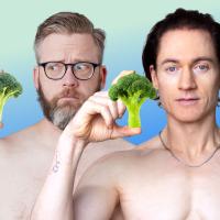 Two men holding broccoli in their hands.