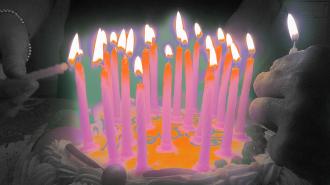A person is lighting lots of candles on a birthday cake.