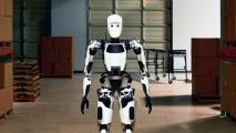 A white and black robot standing in a warehouse.