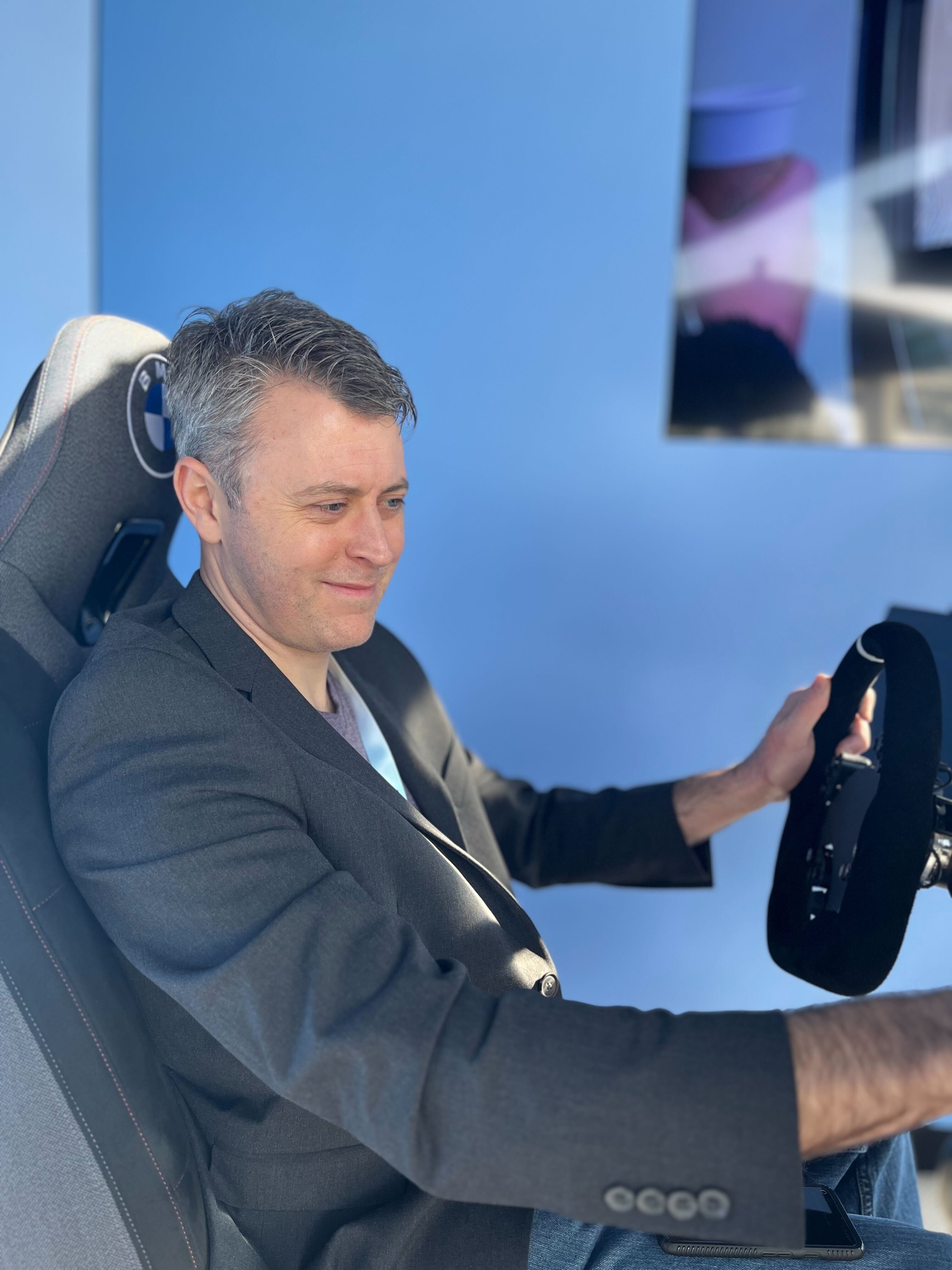 A man in a suit sitting in a driving seat.