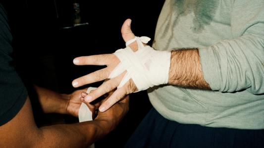 A determined man with a bandage on his hand perseveres through pain for gain.