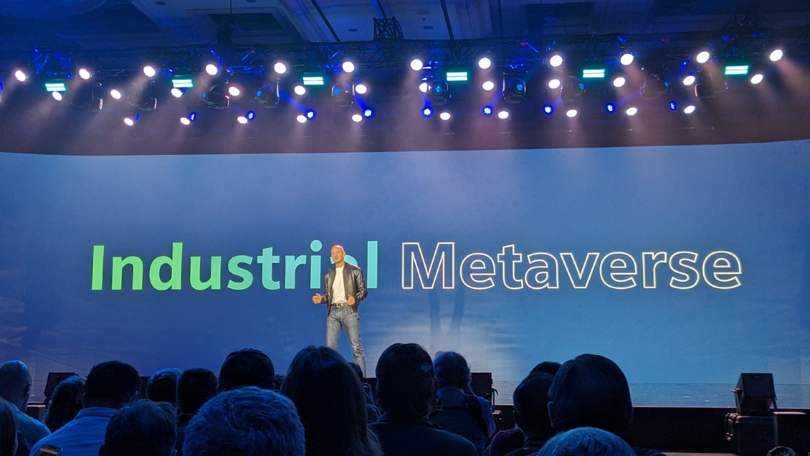 A man on stage at an event with the words industrial metaverse.