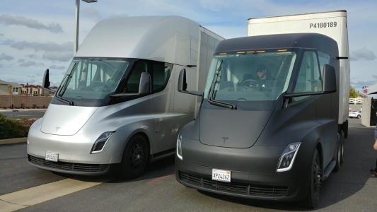 Two electric trucks parked next to each other.