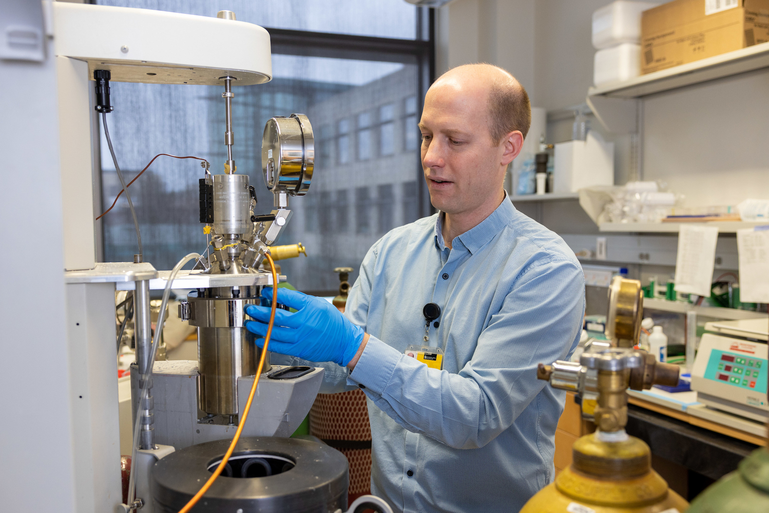 a man wearing gloves is working with a piece of lab equipment