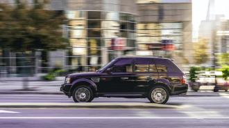 A black land rover driving down a city street.