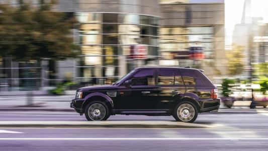 A black land rover driving down a city street.