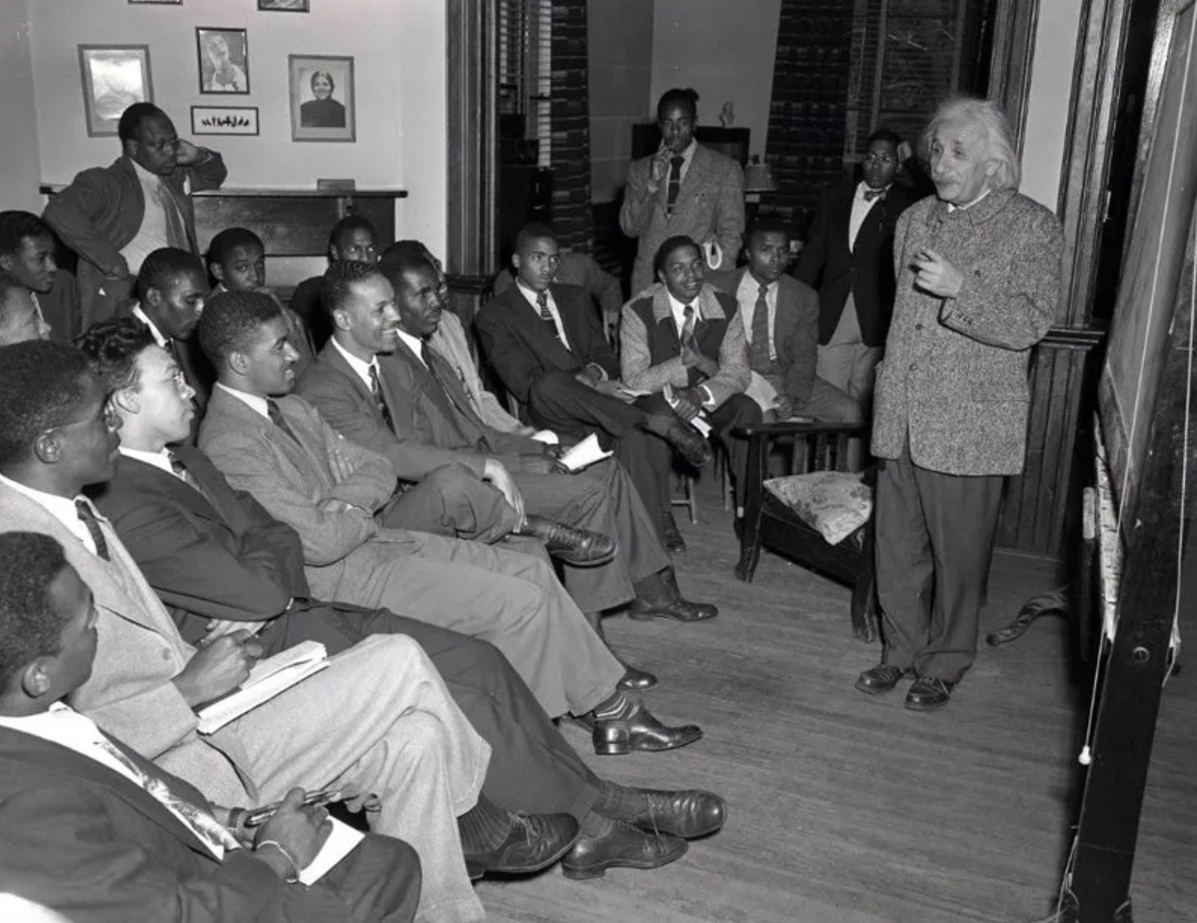 A man in a suit is giving a lecture to a group of people.