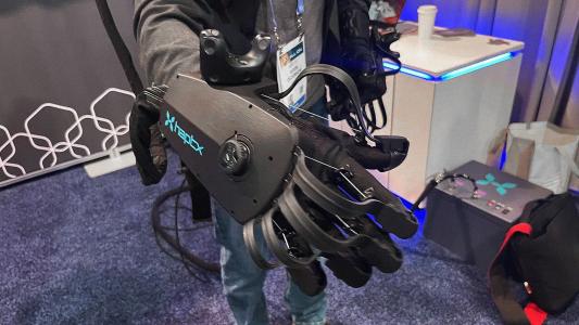 A person holding a robotic glove at a trade show.