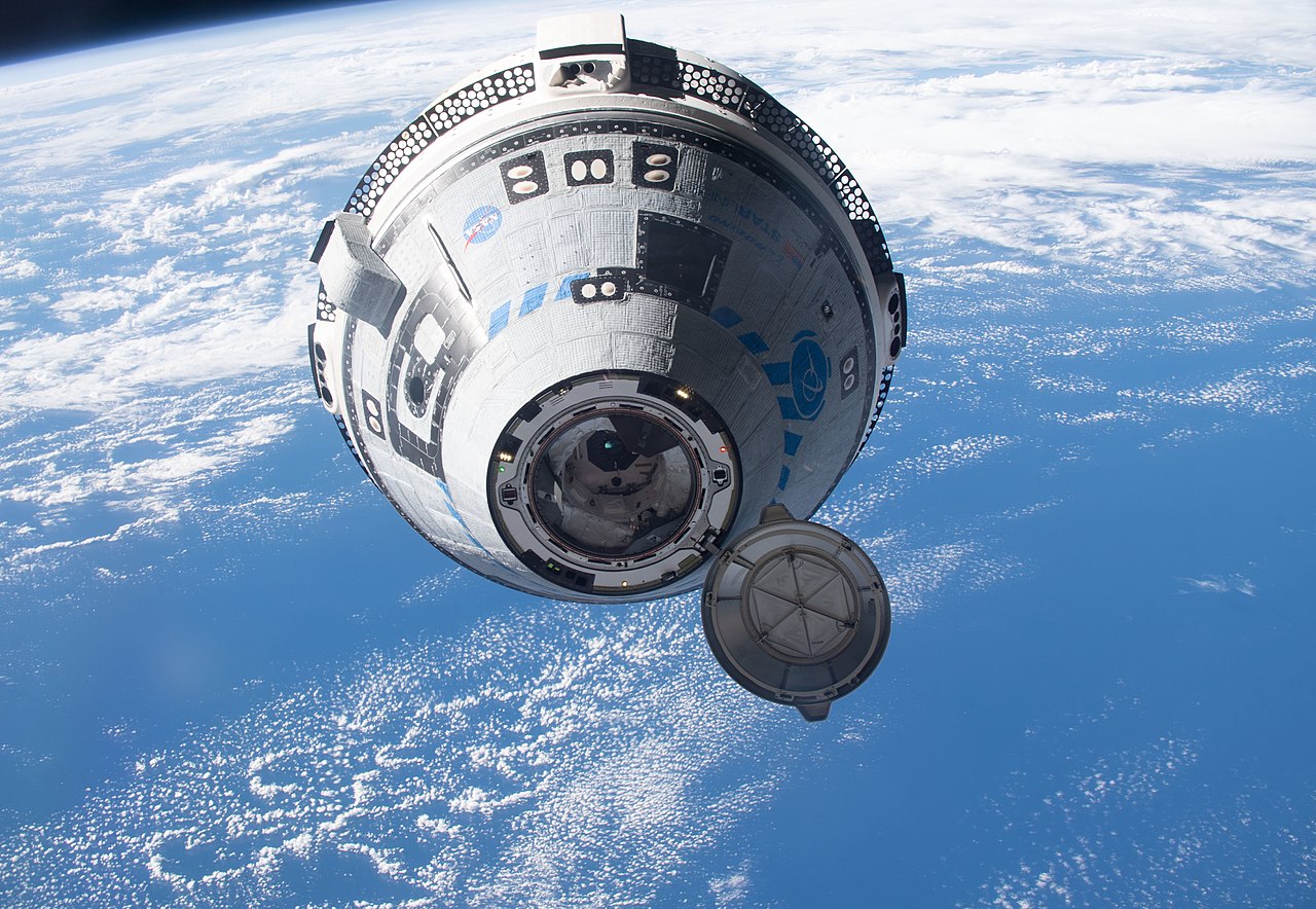 An image of an uncrewed Starliner with Earth in the background
