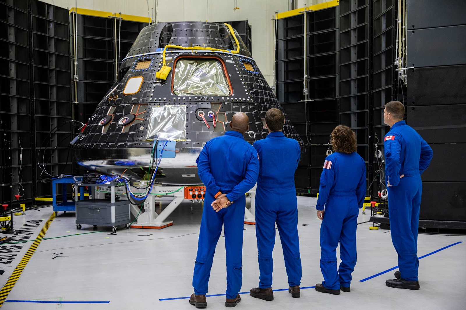 A group of four people in a room looking at a spacecraft.