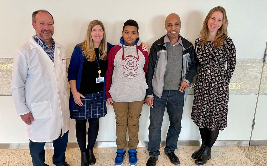 A group of four adults and a child posing for a photo in a hospital.