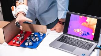 A man is holding a laptop with a thermal sensor on it.