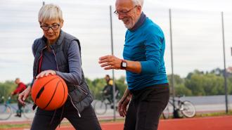 An aging couple playing basketball on a basketball court.