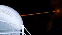 A laser beam is exiting a ground-based space observatory and pointing toward the night sky