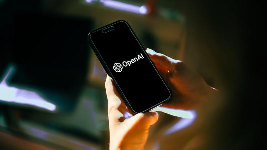 hands holding a phone with the OpenAI logo on the screen