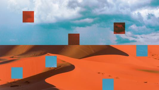 A vibrant red sand dune in the desert with a blue sky