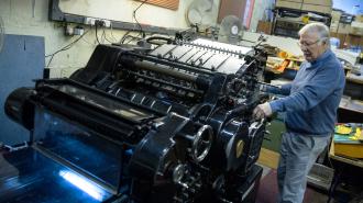 A man working on an old typewriter in a workshop, showcasing his trust in traditional methods of communication.