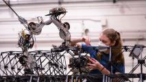 A woman is working with one of NASA's space robots as it builds a structure