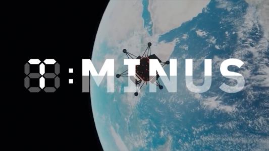 A spacecraft is flying over the Earth with the T-Minus logo on top of the image