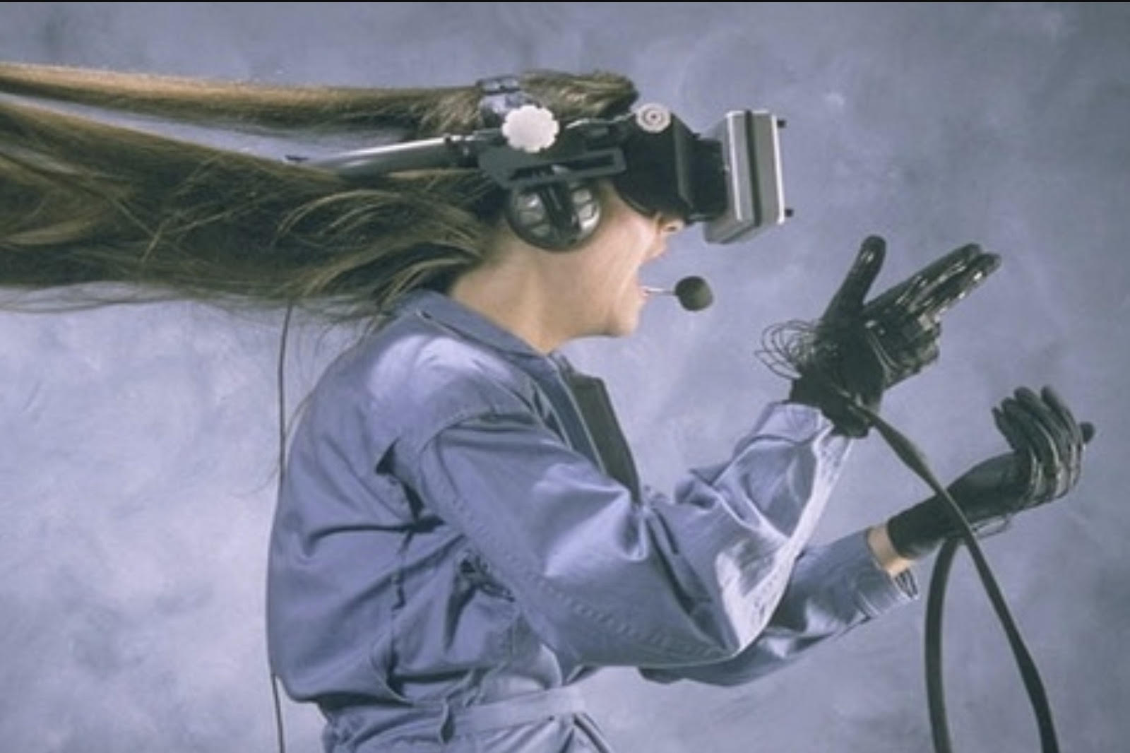 A woman using a VR headset. Her long hair is blowing straight back.