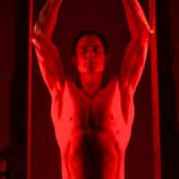 Man performing pull-ups under red lighting.