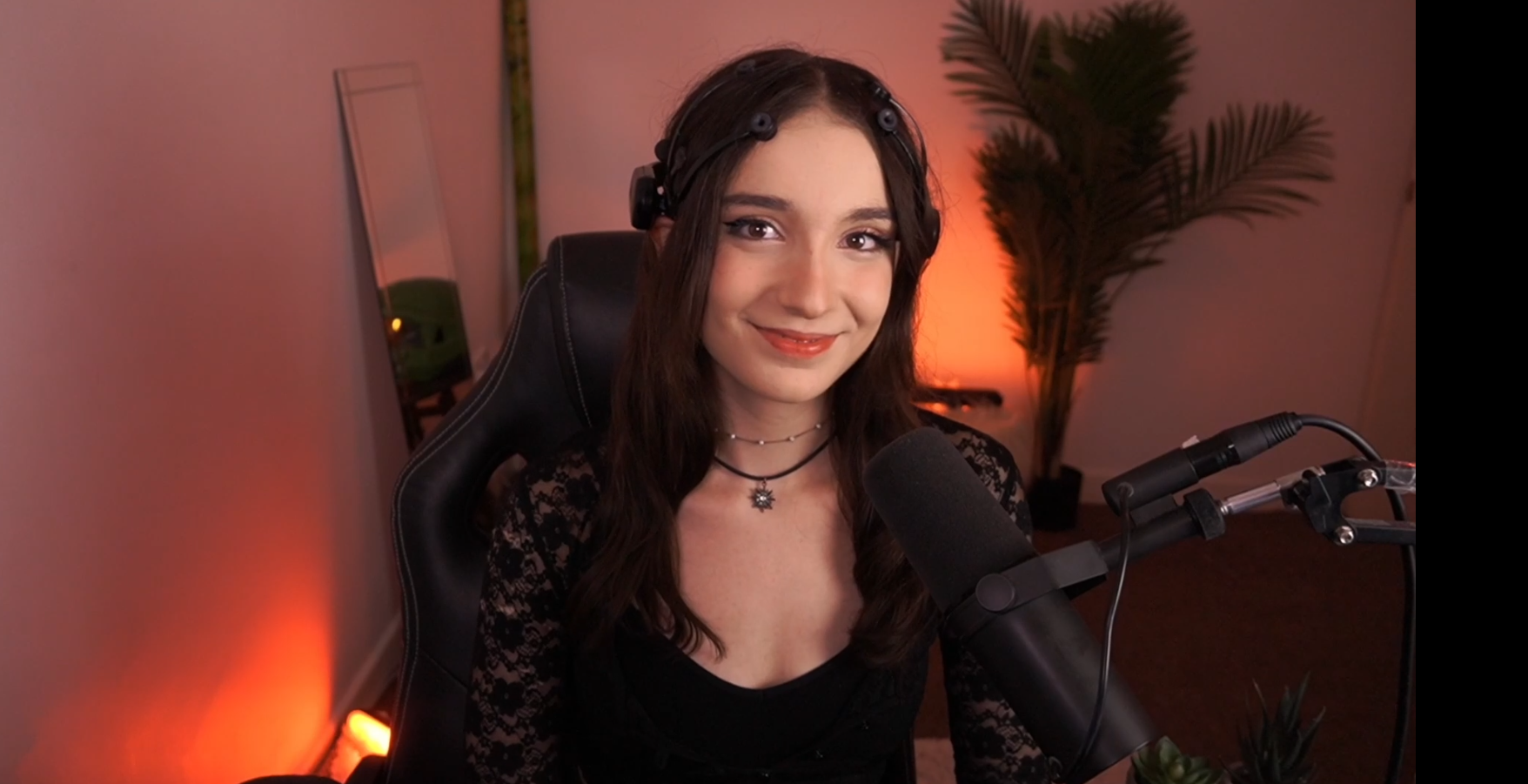 A girl in a black dress sitting in front of a microphone.