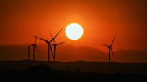 Sunset with wind turbines silhouetted against a vibrant orange sky, showcasing Africa's commitment to clean energy.
