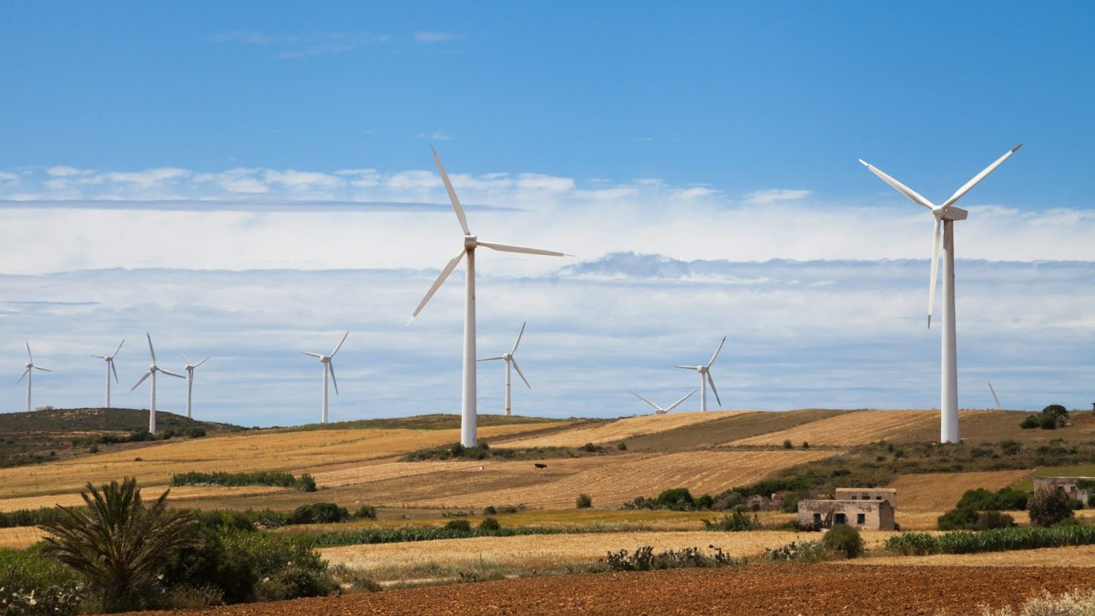 Wind turbines standing in a rural landscape under a clear blue sky.
