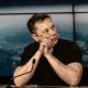 Elon Musk sits behind a microphone