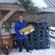 Man holding a honeycomb frame standing next to a stack of black plastic crates in a snowy environment.