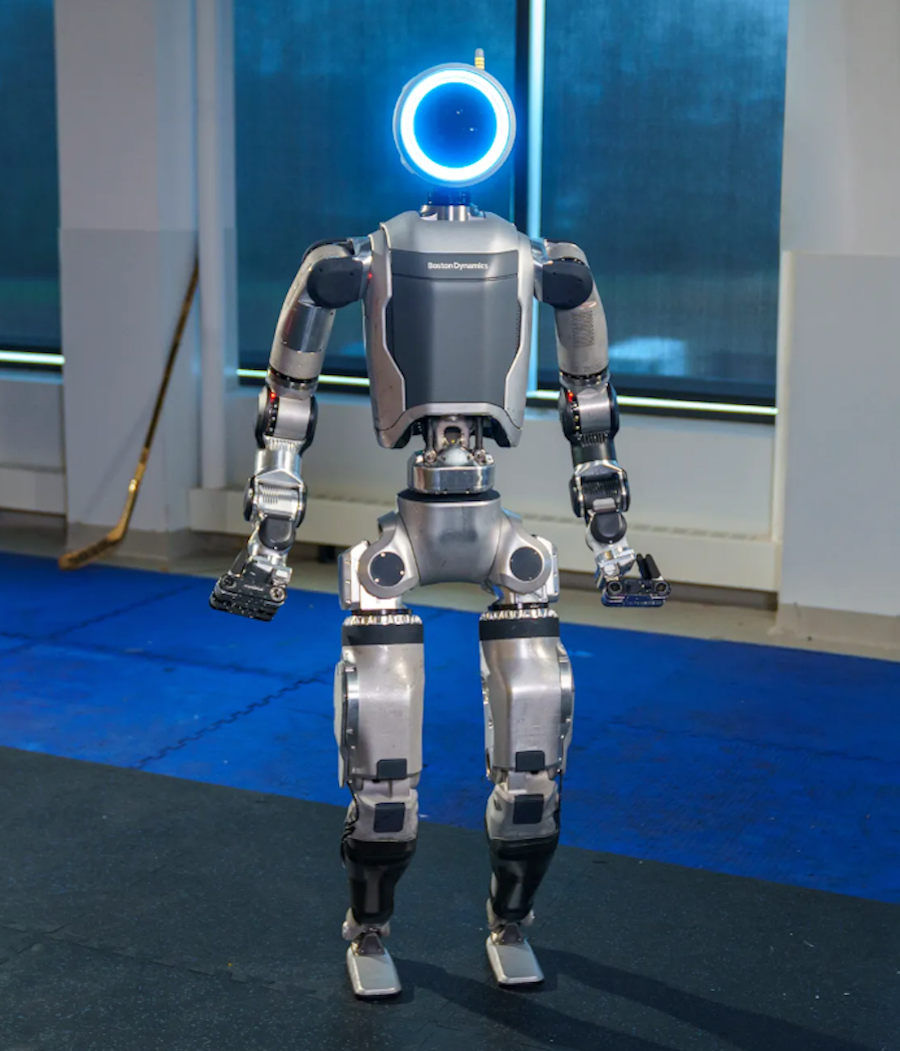 Boston Dynamics' humanoid robot Atlas standing in a room. It has a glowing blue circle for a head