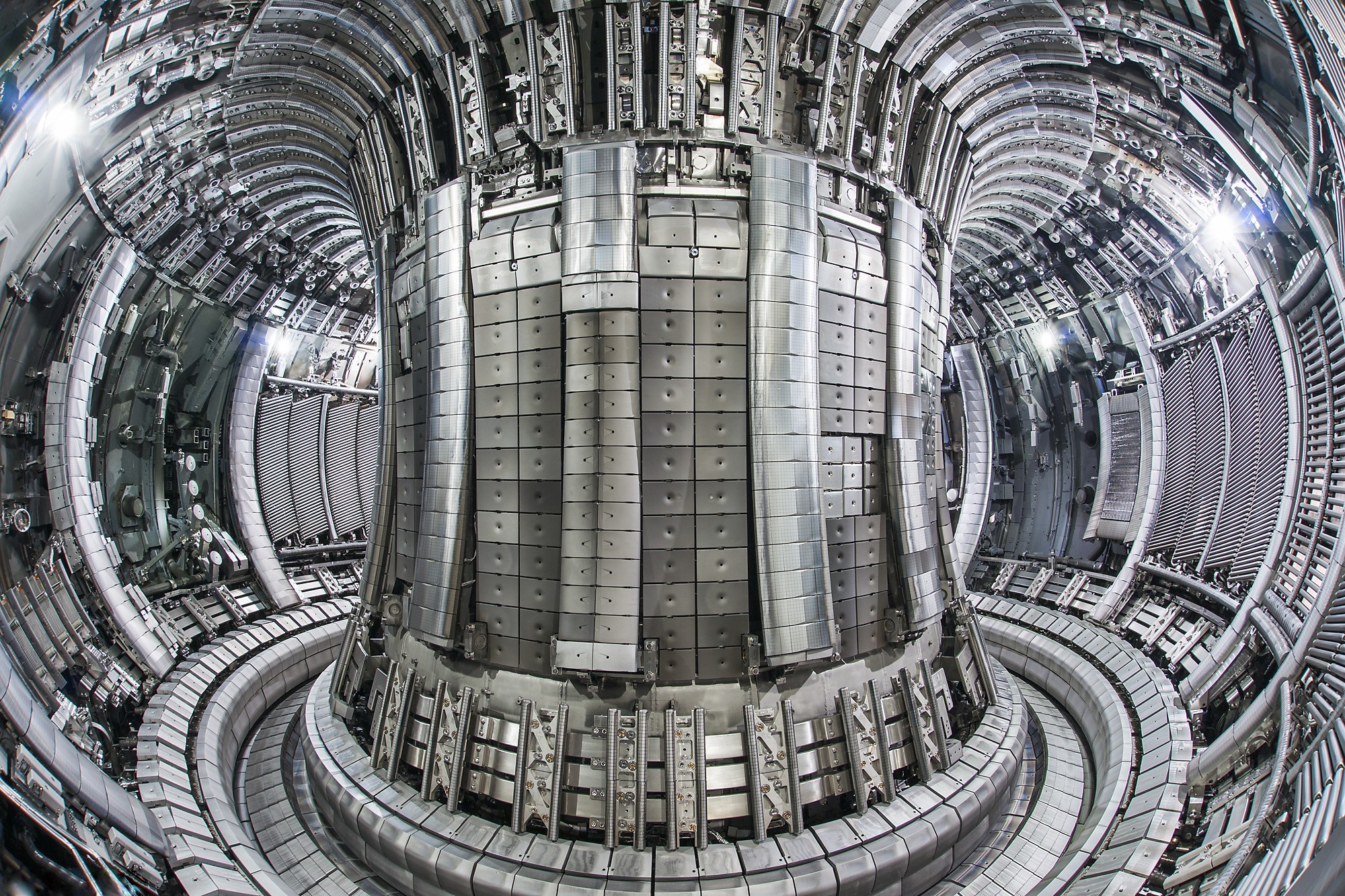 Interior view of a high-tech fusion reactor with a complex array of metallic panels and cylindrical structure.