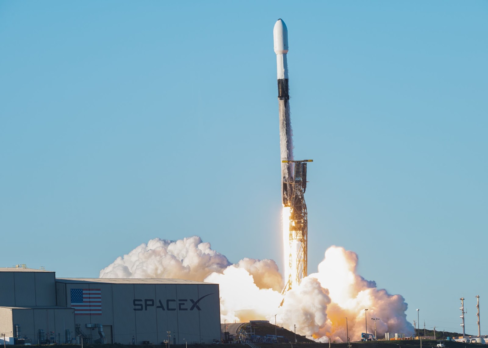 A SpaceX Falcon 9 rocket launching from a ground facility with significant smoke and flame visible.