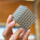 A person holding a complex, 3d-printed metamaterial with a lattice structure