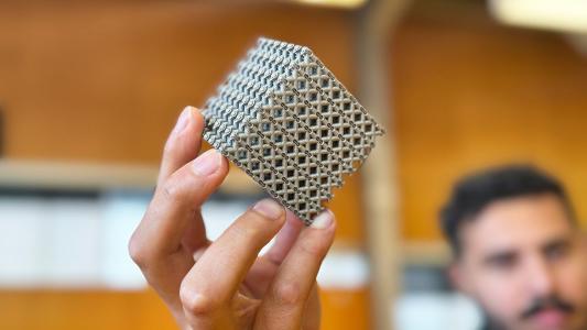 A person holding a complex, 3d-printed metamaterial with a lattice structure