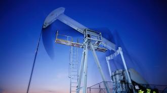 Oil pumpjack operating in the oil fields under a twilight sky.