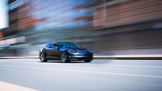 Black electric sedan in motion on a road with motion blur effect.