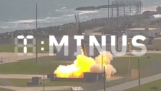 A rocket launch adjacent to a coastal area, emitting a large plume of smoke and flames, with a watermark saying "T-Minus" in the image center.